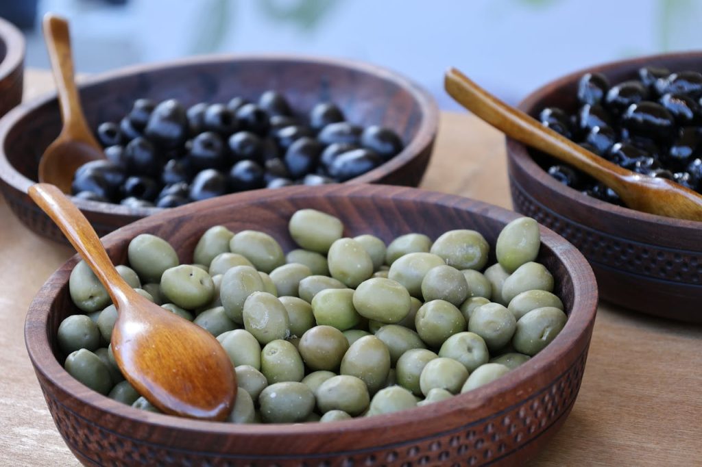 pexels photo 34711354 Close-up of green and black olives in wooden bowls, perfect for culinary themes.